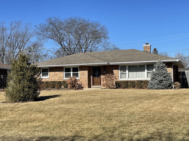 ranch-style house with brick siding, a chimney, a front lawn, and roof with shingles