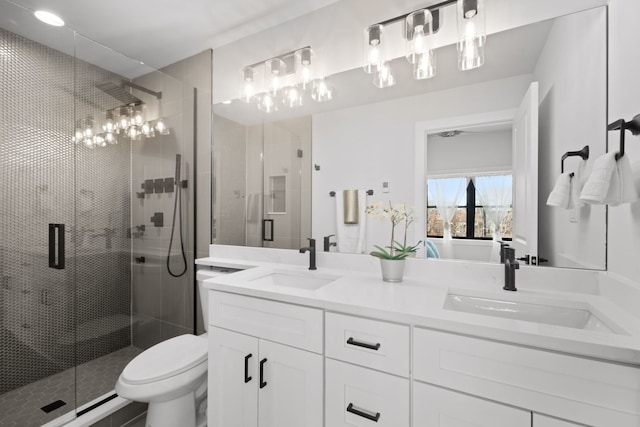 bathroom featuring double vanity, a shower stall, toilet, and a sink