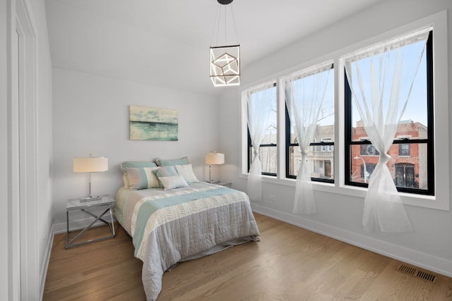 bedroom featuring visible vents, baseboards, and wood finished floors