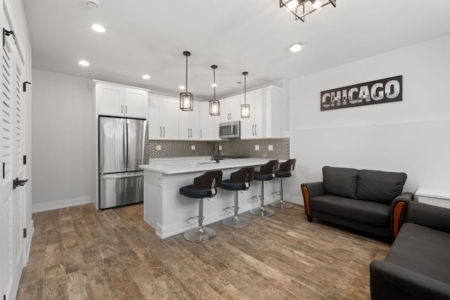 kitchen with a peninsula, decorative backsplash, appliances with stainless steel finishes, a kitchen breakfast bar, and open floor plan