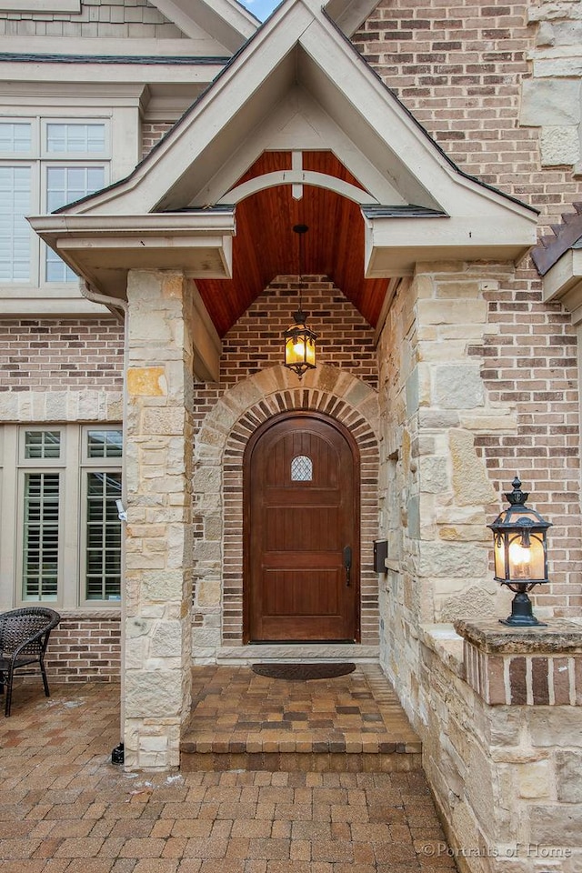 view of exterior entry with brick siding and stone siding