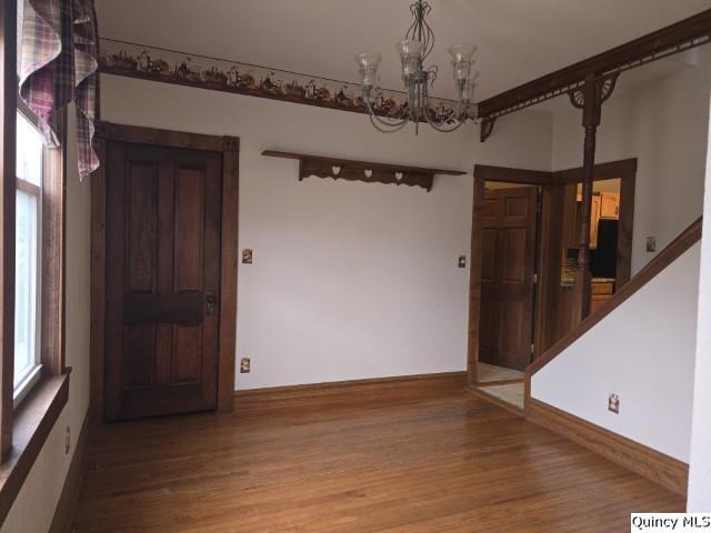 unfurnished room featuring stairway, wood finished floors, and a chandelier