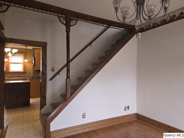 stairs with an inviting chandelier and baseboards