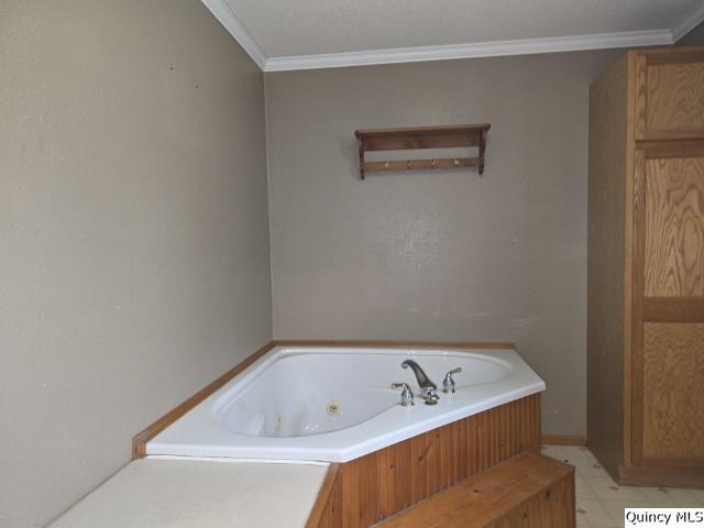 bathroom with crown molding, a jetted tub, and tile patterned floors