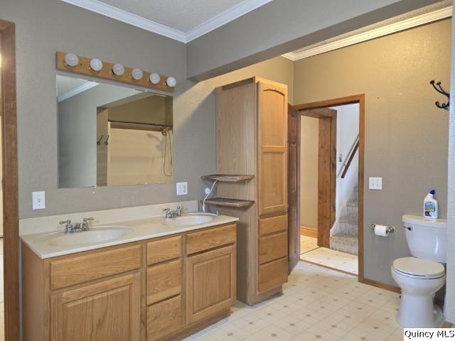 full bath with double vanity, a sink, ornamental molding, tile patterned floors, and toilet