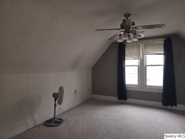 bonus room featuring baseboards, vaulted ceiling, carpet floors, a textured ceiling, and a ceiling fan