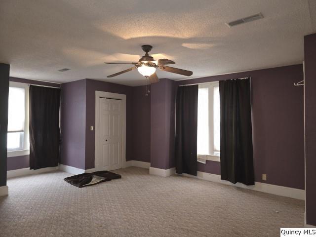 unfurnished room featuring visible vents, ceiling fan, baseboards, carpet floors, and a textured ceiling