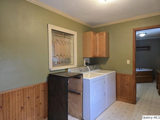 laundry area with wooden walls, washing machine and dryer, light floors, wainscoting, and cabinet space