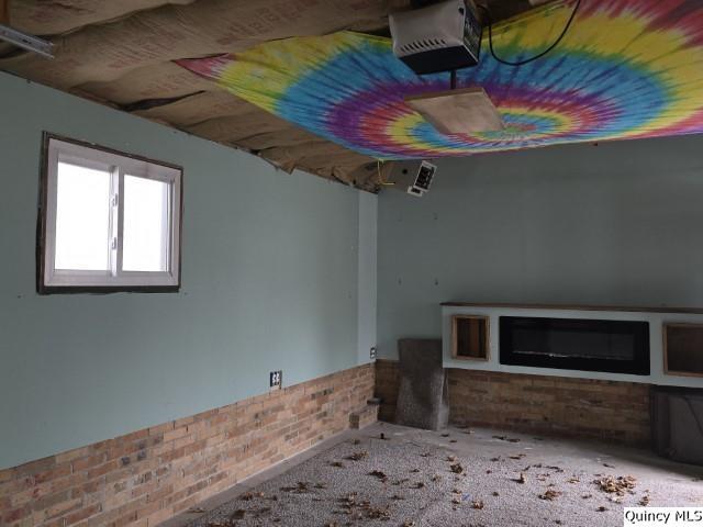 unfurnished living room featuring brick wall