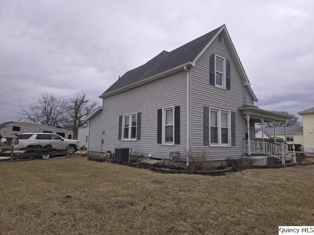 view of home's exterior with covered porch, a lawn, and central AC