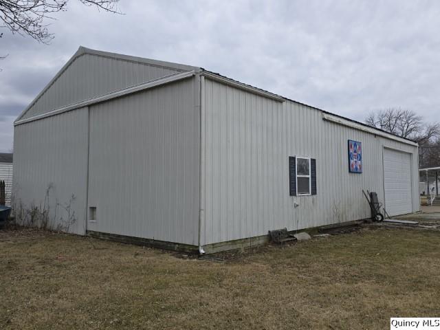 view of property exterior with an outbuilding, a detached garage, and a yard