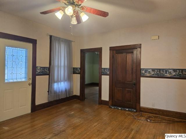 foyer entrance with baseboards, wood finished floors, and a ceiling fan