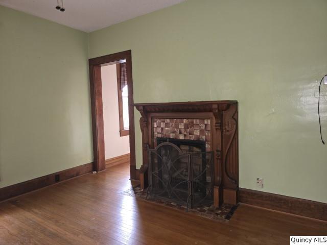 unfurnished living room featuring wood finished floors, baseboards, and a tile fireplace