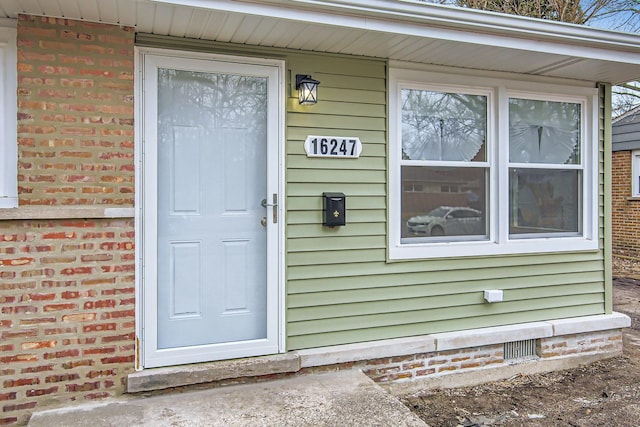 doorway to property with brick siding and crawl space