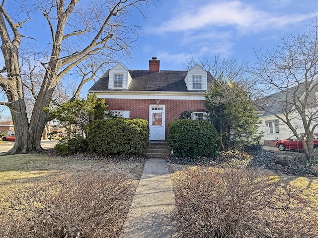 view of front of property with entry steps, brick siding, and a chimney