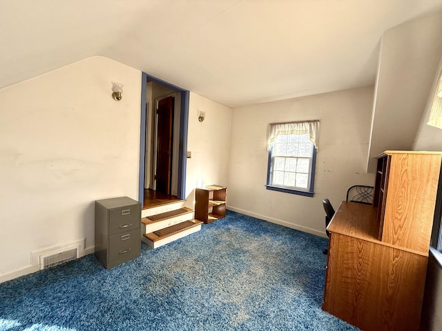 office space with vaulted ceiling, visible vents, baseboards, and dark colored carpet