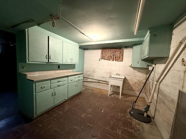 kitchen with concrete block wall, light countertops, and green cabinetry