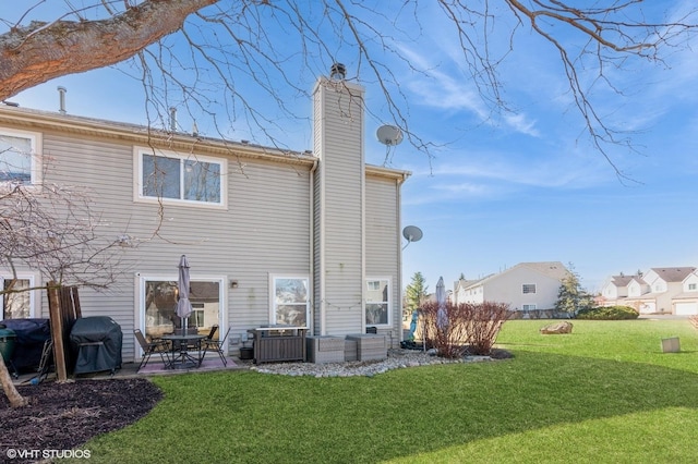 rear view of house featuring a yard, a patio, and a chimney