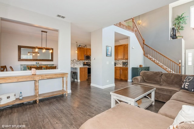 living area featuring stairs, dark wood-style floors, visible vents, and baseboards