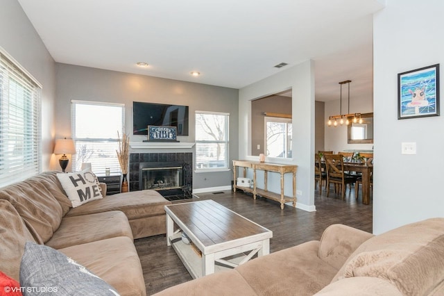 living room with a fireplace, dark wood-style flooring, a wealth of natural light, and baseboards