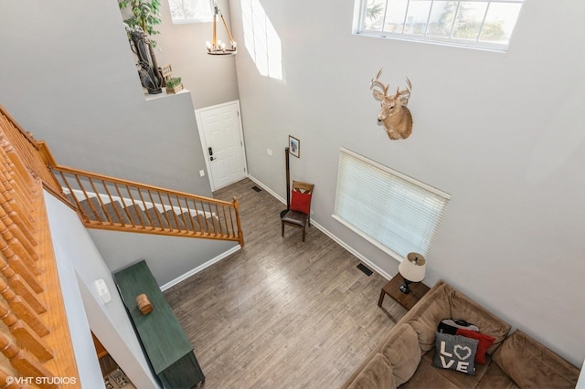 entryway featuring visible vents, a notable chandelier, wood finished floors, stairway, and baseboards