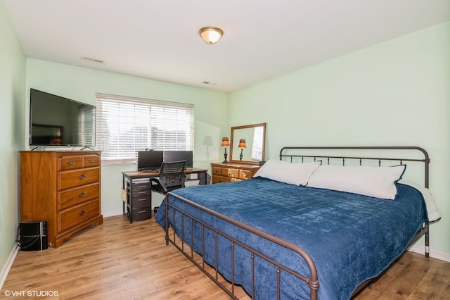 bedroom featuring wood finished floors, visible vents, and baseboards