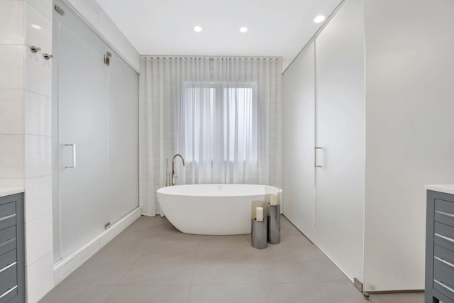 full bath with vanity, a soaking tub, recessed lighting, and tile patterned floors