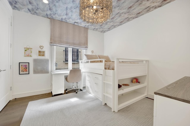 bedroom with baseboards, an inviting chandelier, and wood finished floors