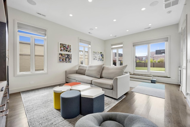 living room with recessed lighting, wood finished floors, and visible vents