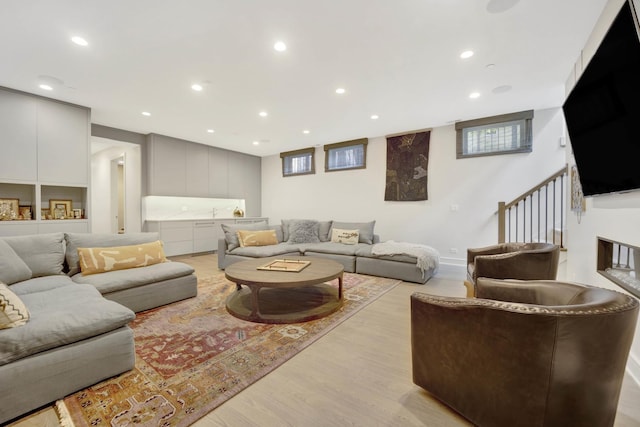 living area with light wood finished floors, stairway, and recessed lighting