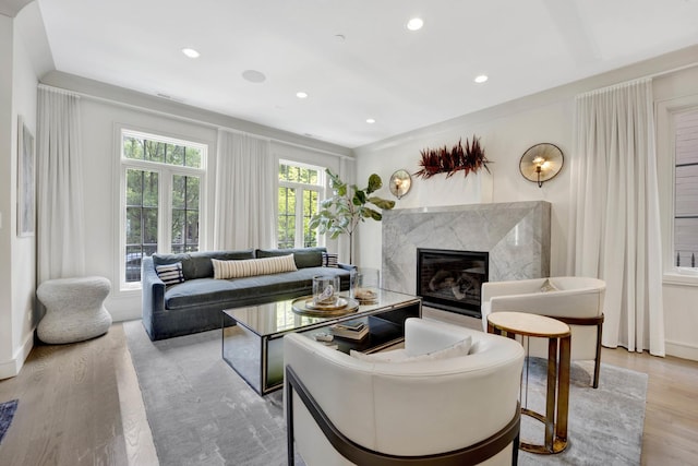 living room featuring recessed lighting, light wood-style flooring, and a high end fireplace