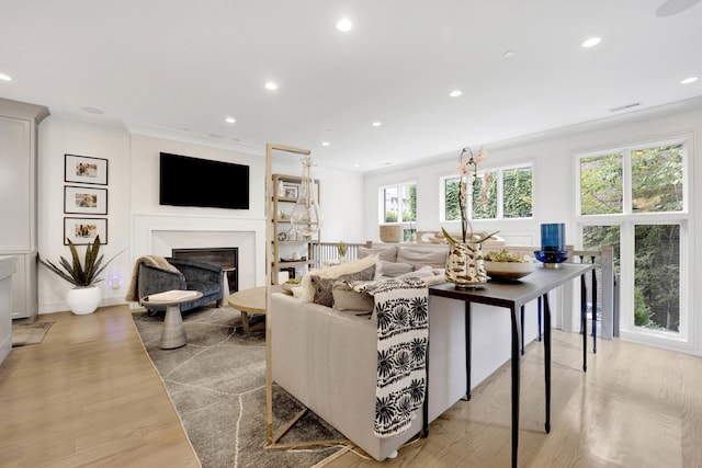 living area featuring visible vents, ornamental molding, recessed lighting, light wood-style floors, and a fireplace