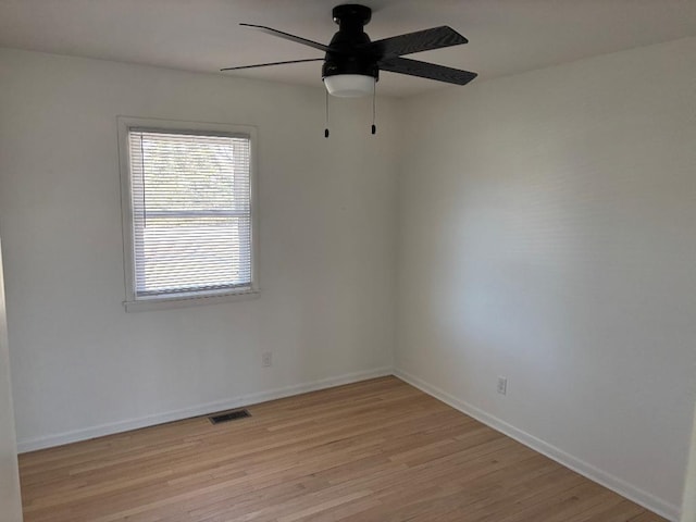 unfurnished room with visible vents, light wood-style flooring, a ceiling fan, and baseboards