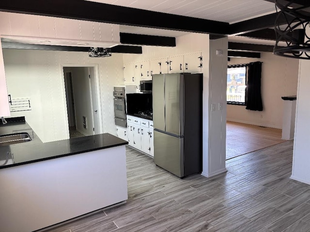 kitchen with dark countertops, beamed ceiling, black appliances, and light wood-type flooring