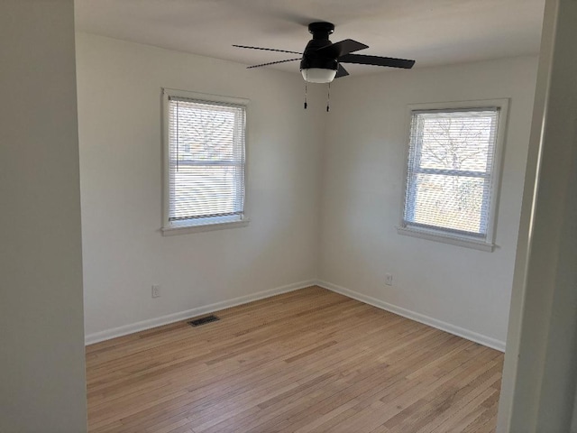 empty room featuring baseboards, a healthy amount of sunlight, and light wood finished floors