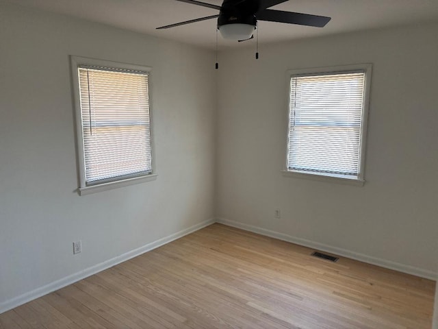 spare room featuring visible vents, plenty of natural light, baseboards, and light wood-style flooring