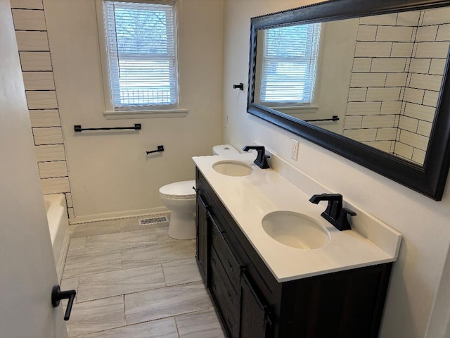 bathroom with double vanity, toilet, visible vents, and a sink