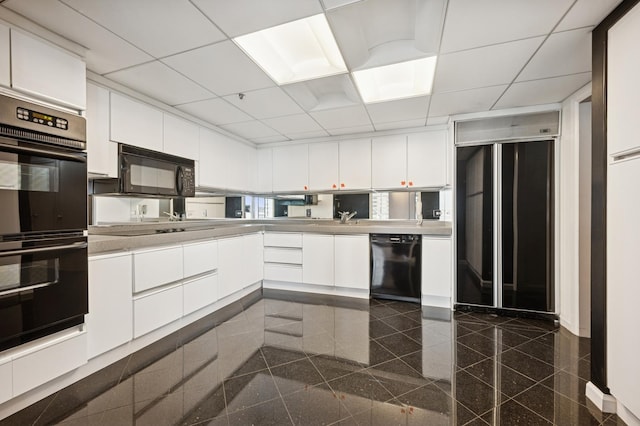 kitchen featuring granite finish floor, a drop ceiling, black appliances, and light countertops