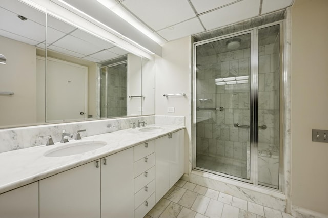 bathroom with a sink, marble finish floor, a stall shower, and double vanity