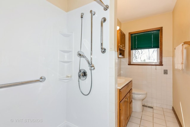 bathroom with toilet, tile walls, tile patterned flooring, a shower, and vanity