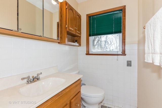 bathroom with vanity, toilet, and tile walls