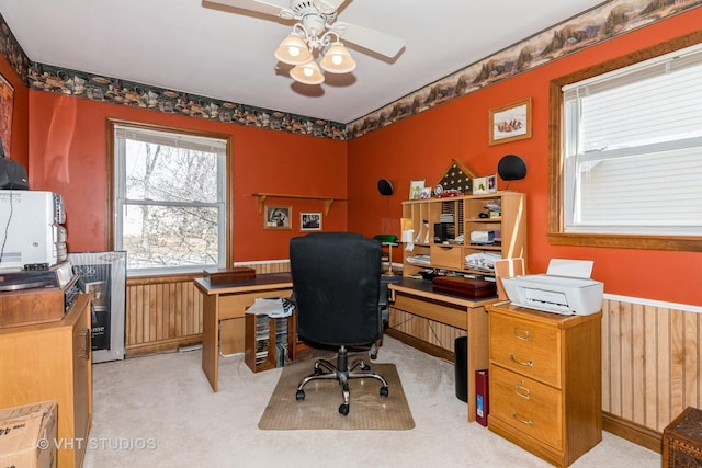 office featuring a wainscoted wall, light colored carpet, and a ceiling fan