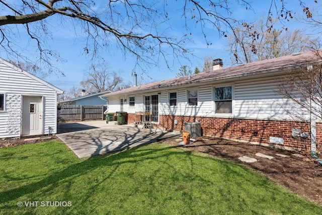 rear view of property with a yard, brick siding, a patio, and fence