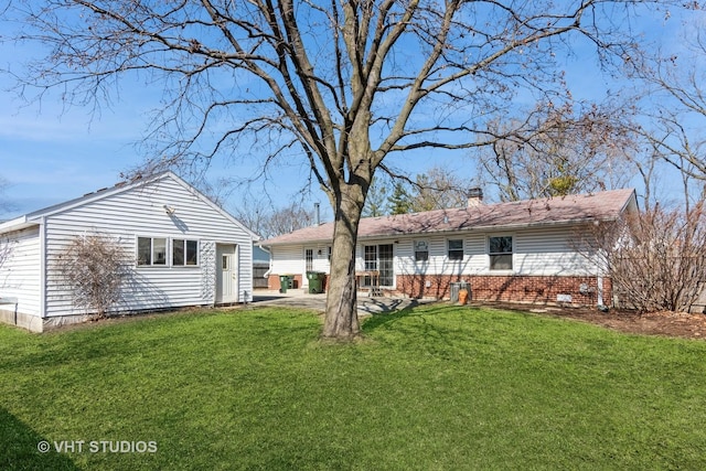 rear view of house featuring a patio, a lawn, and a chimney