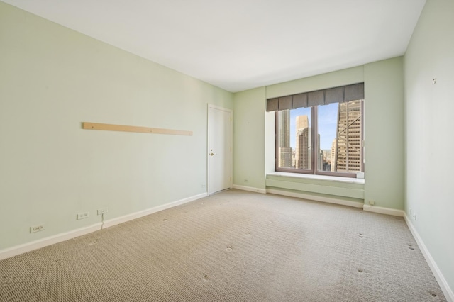 spare room with a view of city, carpet, and baseboards