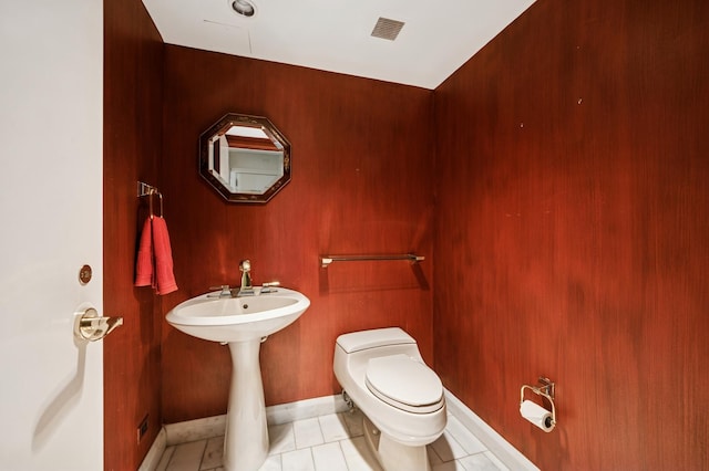 half bathroom featuring tile patterned flooring, visible vents, toilet, and baseboards