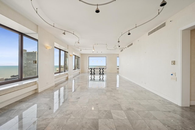 corridor featuring rail lighting, baseboards, and visible vents