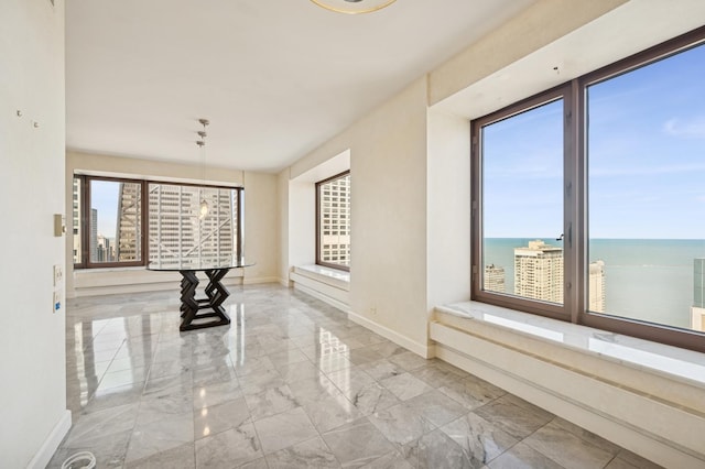 corridor with a water view, baseboards, marble finish floor, and a wealth of natural light