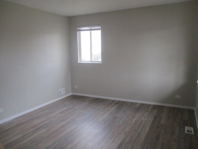 spare room with visible vents, baseboards, and wood finished floors