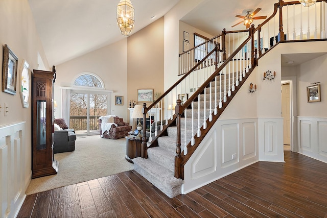 entryway featuring a wainscoted wall, stairway, a towering ceiling, dark wood-style floors, and a decorative wall